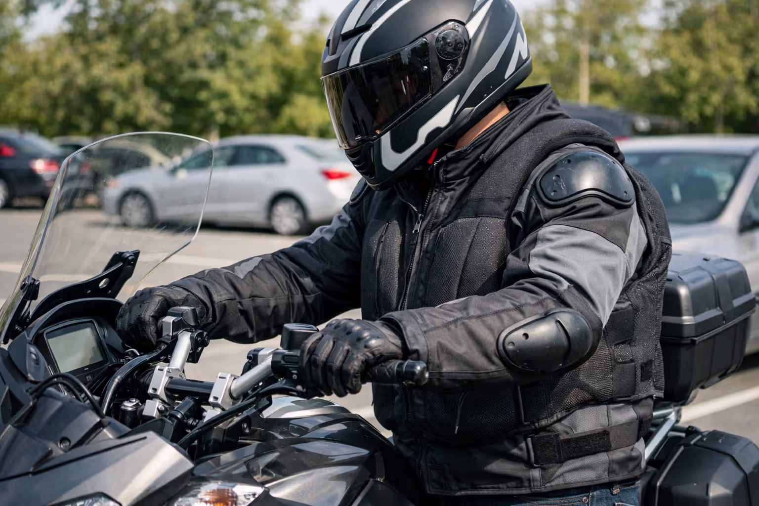 Motorcyclist wearing protective jacket with CE shoulder armor and airbag vest standing next to a touring motorcycle with raised handlebars
